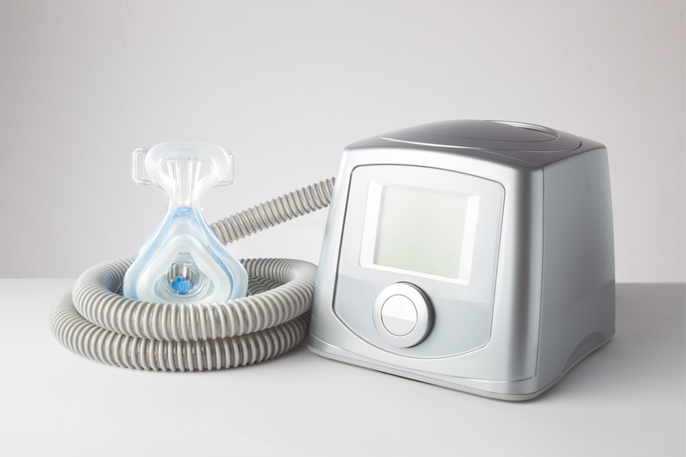 CPAP machine with mask and hose on gray background