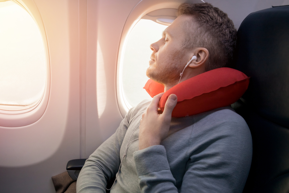 Man using neck pillow on airplane