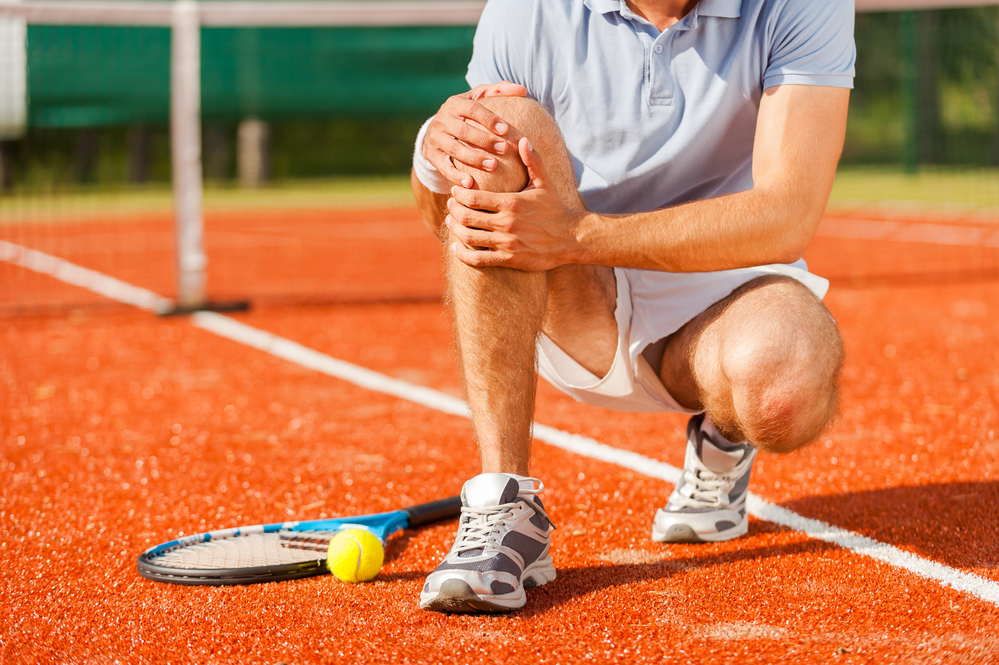 Man on tennis court holding his knee