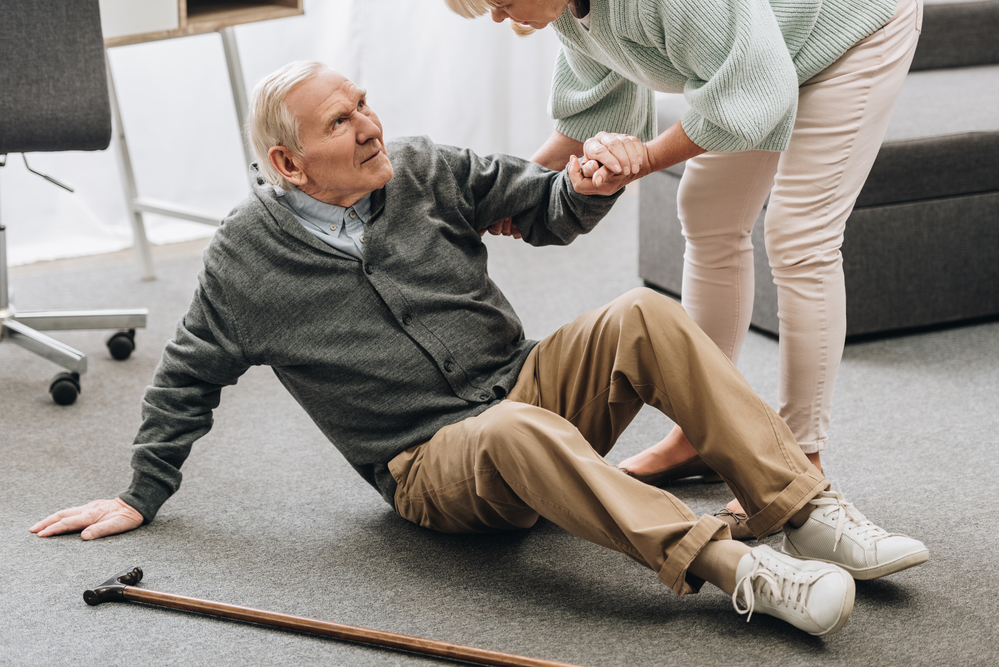 Elderly man on the ground while a woman helps him up