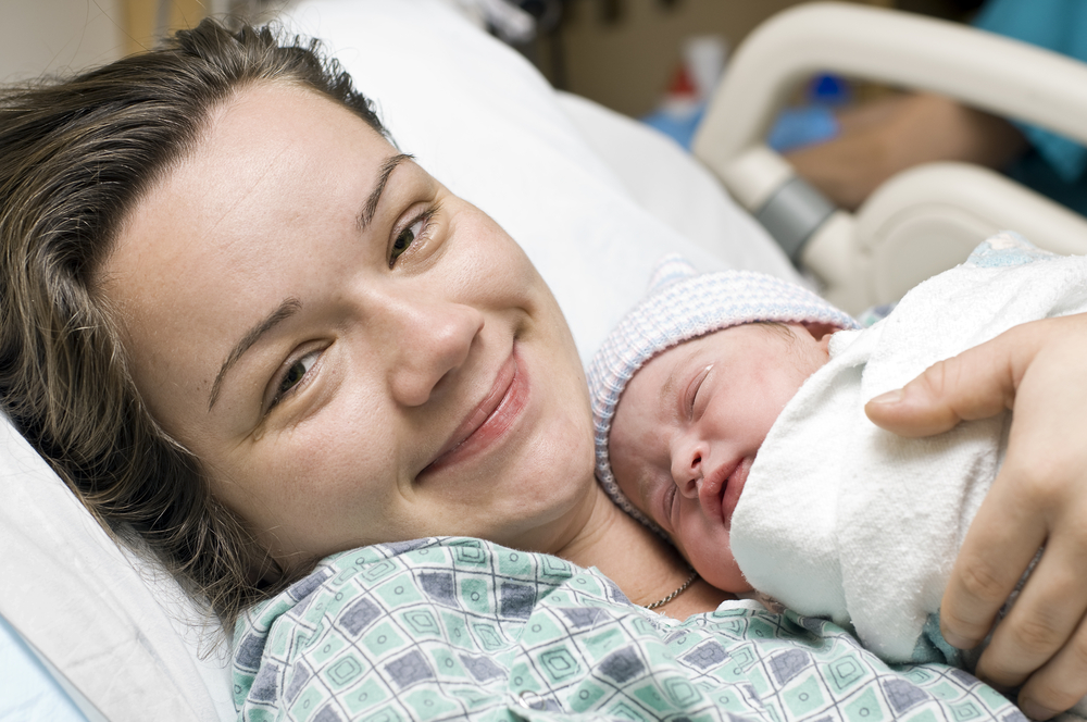 Woman holding newborn baby in hospital bed