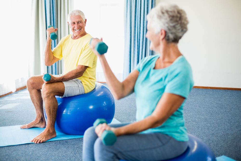 Senior couple on exercise balls with weights