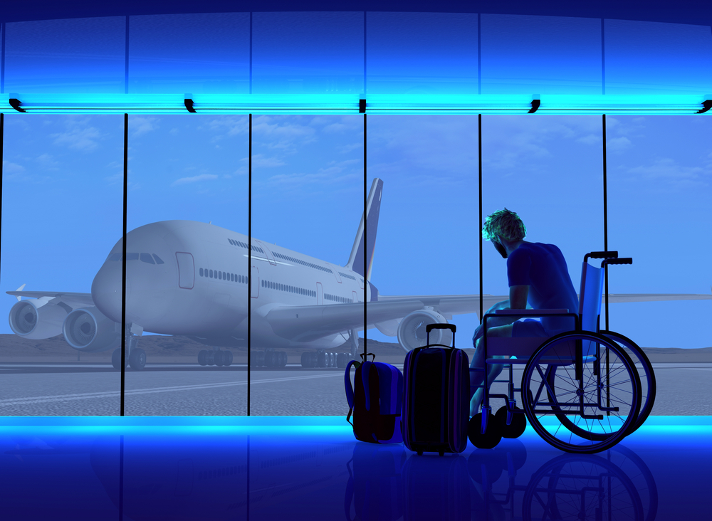 Man in wheelchair with luggage looking out at plane