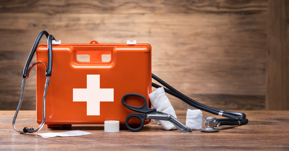 First aid kit and medical supplies on wooden background