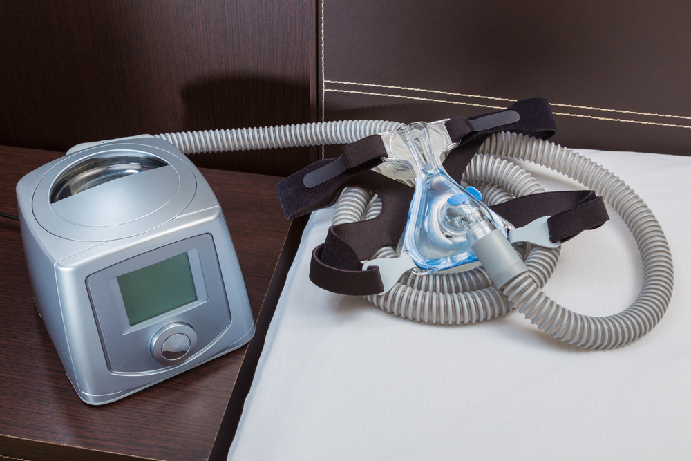 CPAP machine and headgear beside bed