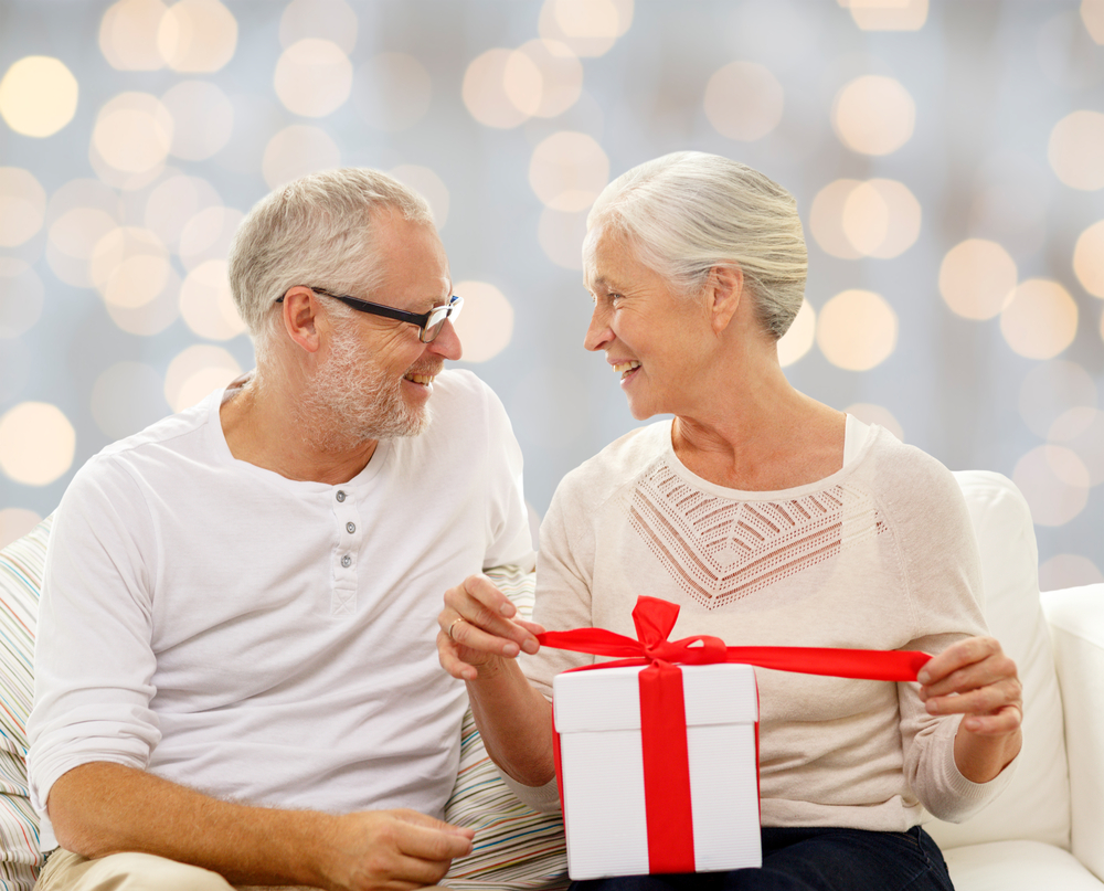 Senior couple on couch opening gift box