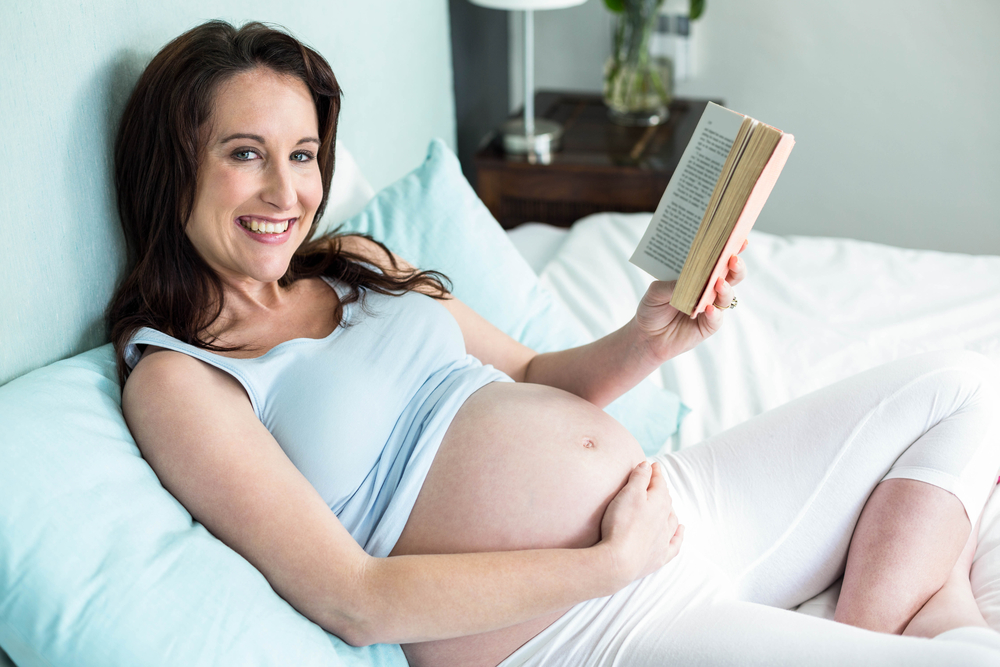 Pregnant woman reading in bed