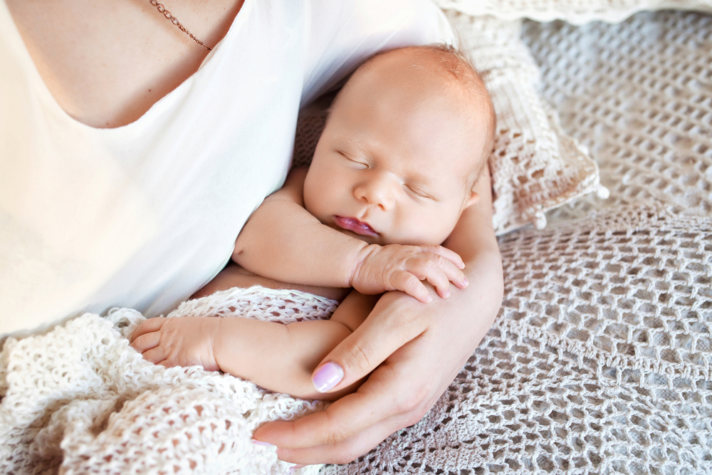 newborn baby sleeping in mother's arms