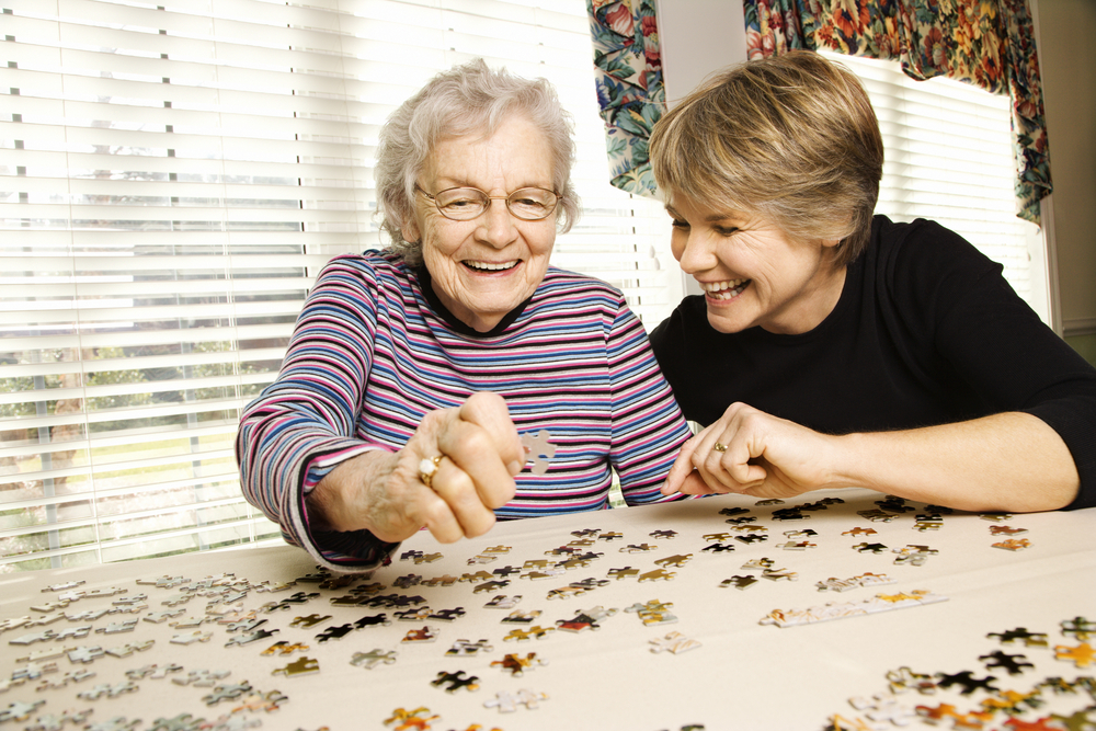 Young woman and elderly woman doing puzzle together