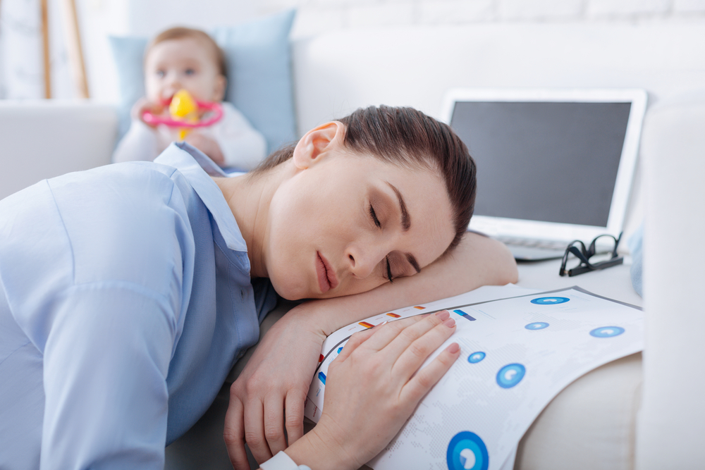 Young woman resting on paperwork with baby nearby