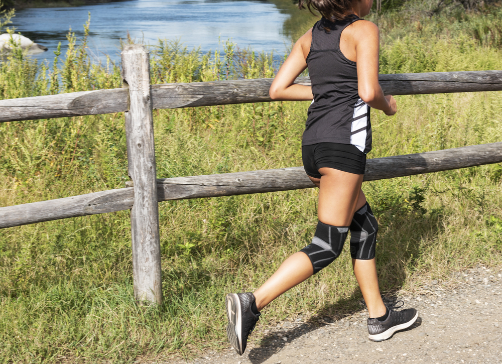 Woman running outdoors with knee support braces