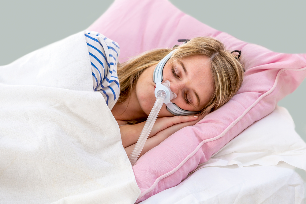 Young woman sleeping with CPAP machine on