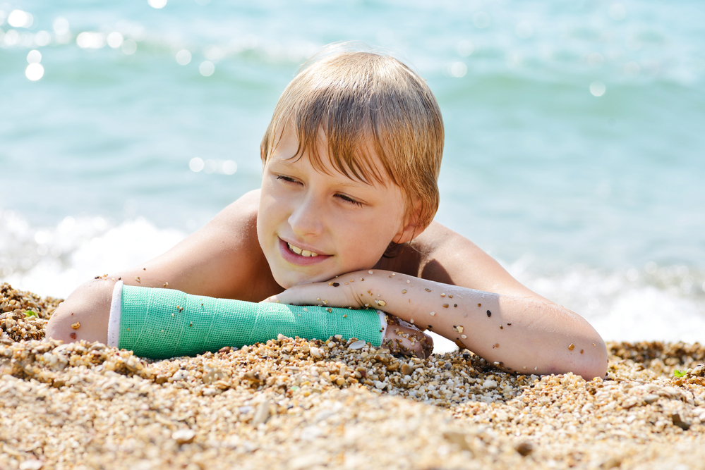 Boy wearing cast on beach