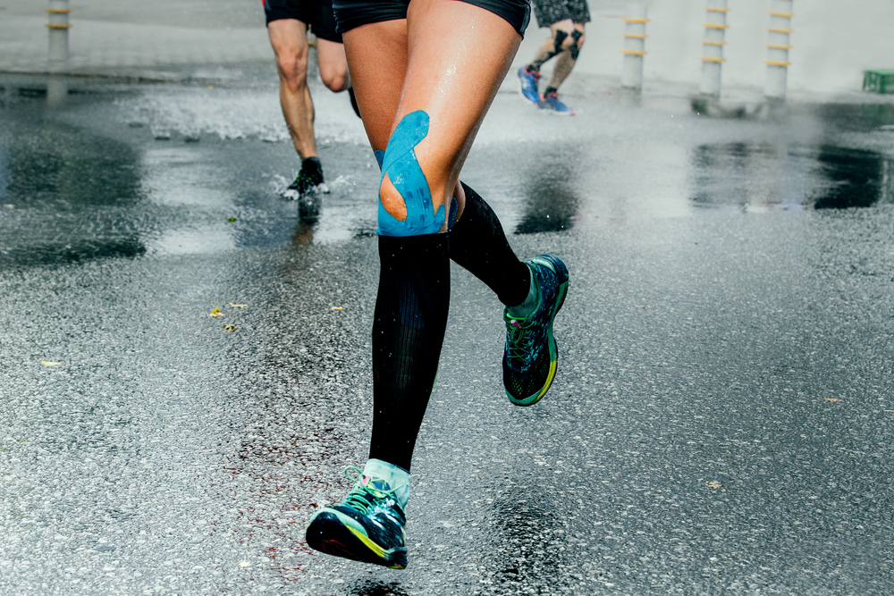 Feet of female runner wearing compression socks and athletic tape